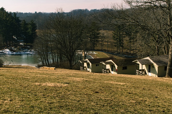 Grassy hill with cabins and lake in background